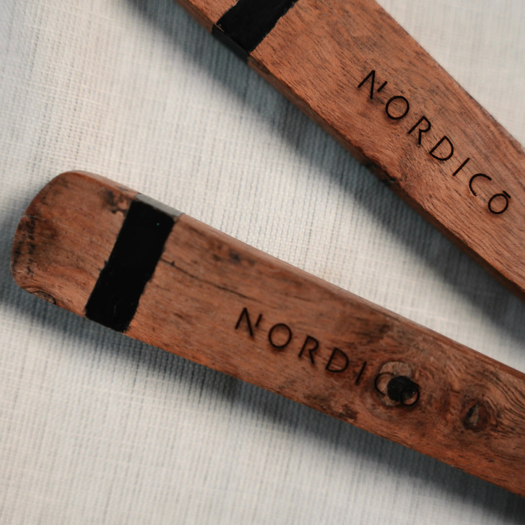 Close-up of Nordico wooden salad servers with engraved branding on the acacia wood handles.