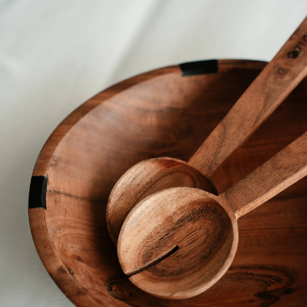 Close-up of Nordico wooden salad servers with engraved branding on the acacia wood handles.