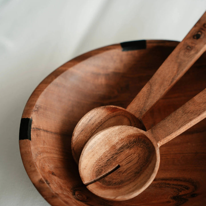 Close-up of Nordico wooden salad servers with engraved branding on the acacia wood handles.