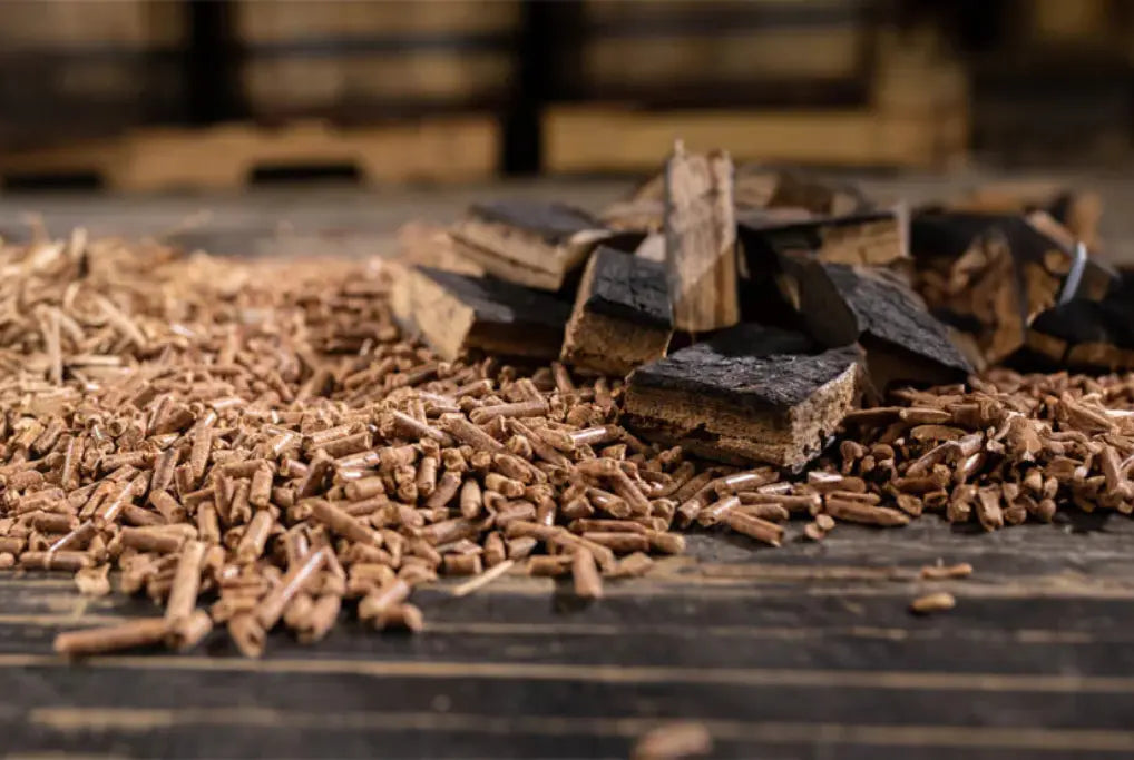 Natural hardwood chips and chunks spread on a wooden surface, perfect for smoking and grilling to infuse rich, smoky flavors into BBQ dishes.