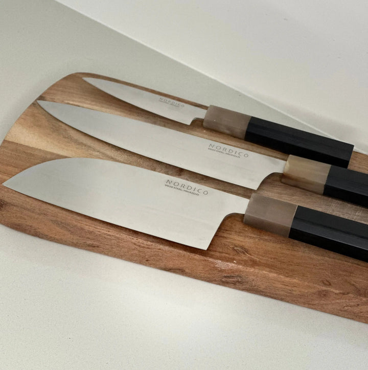 Set of three Nordico VG10 knives on a wooden cutting board, showcasing the cleaver, chef, and paring knives together.