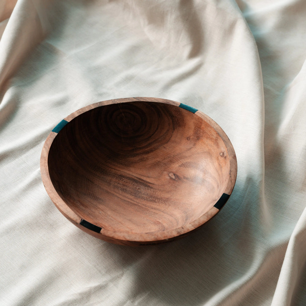 NORDICO wooden bowl made of acacia wood with an irregular shape placed on a soft linen fabric.