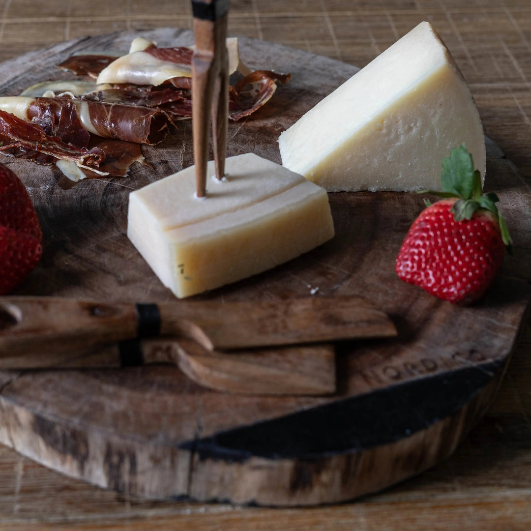 Nordico Cheese Board Set with Cheese and Strawberries – Acacia wooden cheese board with cheese wedges, cured meat, and fresh strawberries arranged, featuring Nordico wooden cheese knives.