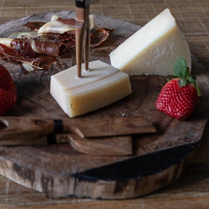 Nordico Cheese Board Set with Cheese and Strawberries – Acacia wooden cheese board with cheese wedges, cured meat, and fresh strawberries arranged, featuring Nordico wooden cheese knives.
