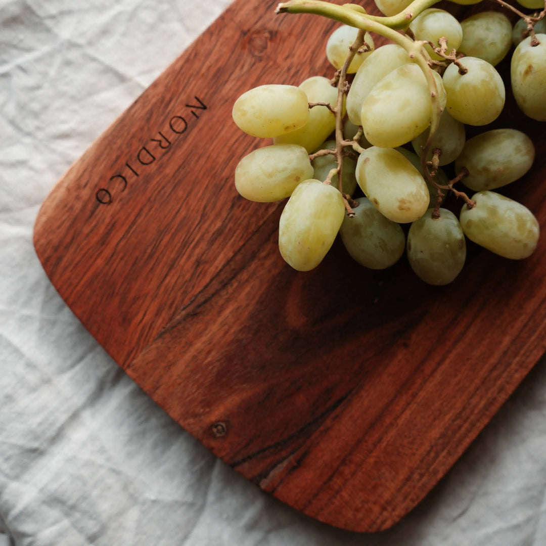 Nordico acacia wood cutting board featuring fresh green grapes, highlighting its natural wood grain.