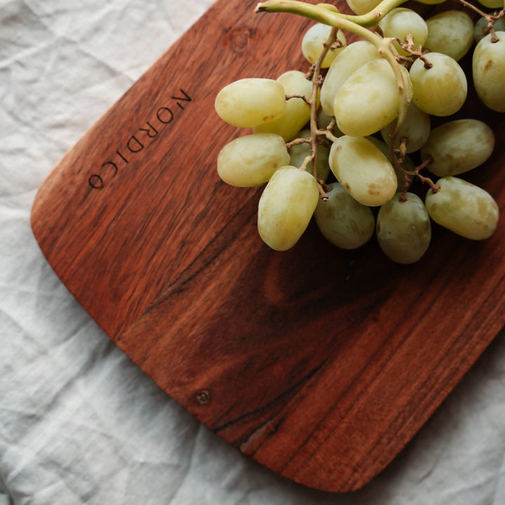 Nordico acacia wood cutting board featuring fresh green grapes, highlighting its natural wood grain.