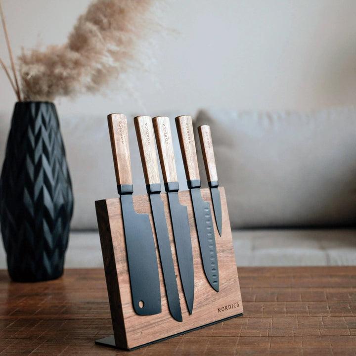 Luxury Nordico 5-piece stainless steel kitchen knives set with acacia handles on a modern wooden table.